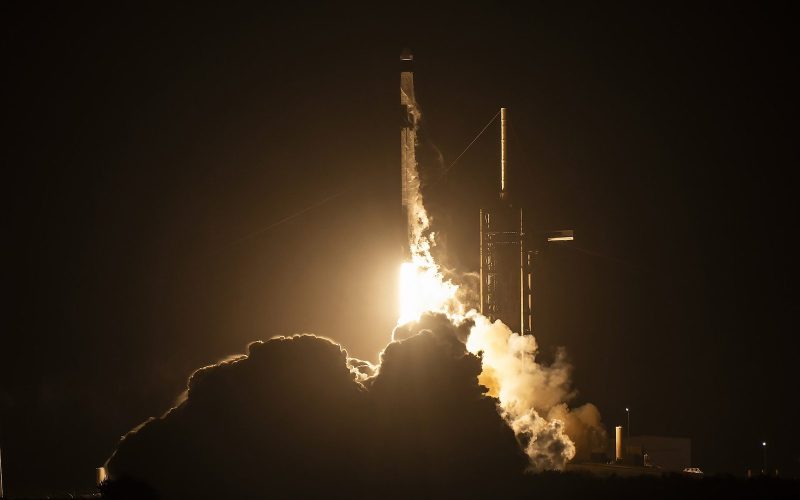 SpaceX Falcon 9 rocket lifting off at night from Kennedy Space Center, lighting up a cloud of exhaust