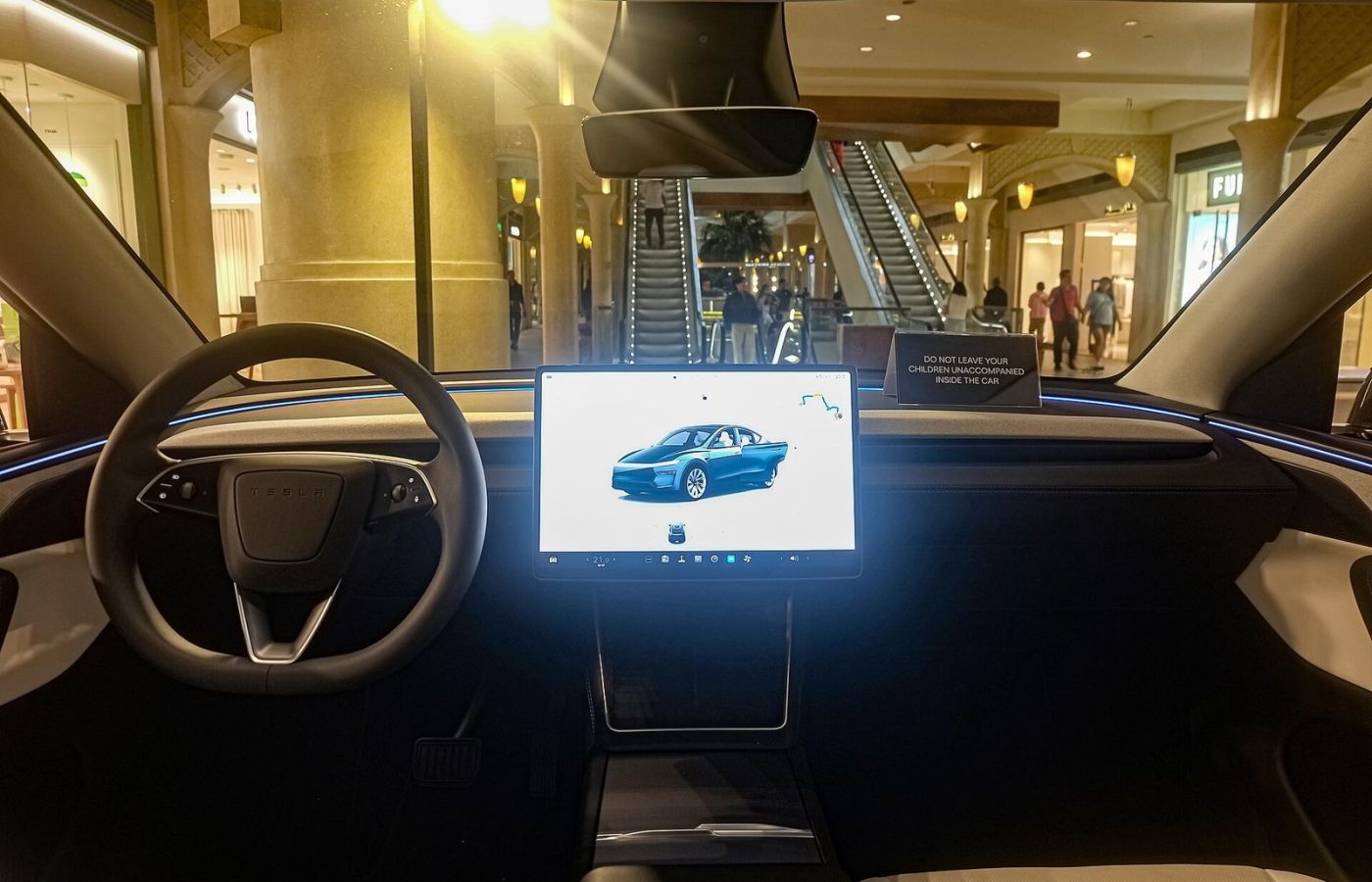 Driver's view of a refreshed Tesla Model Y interior with steering wheel and lit centre touchscreen