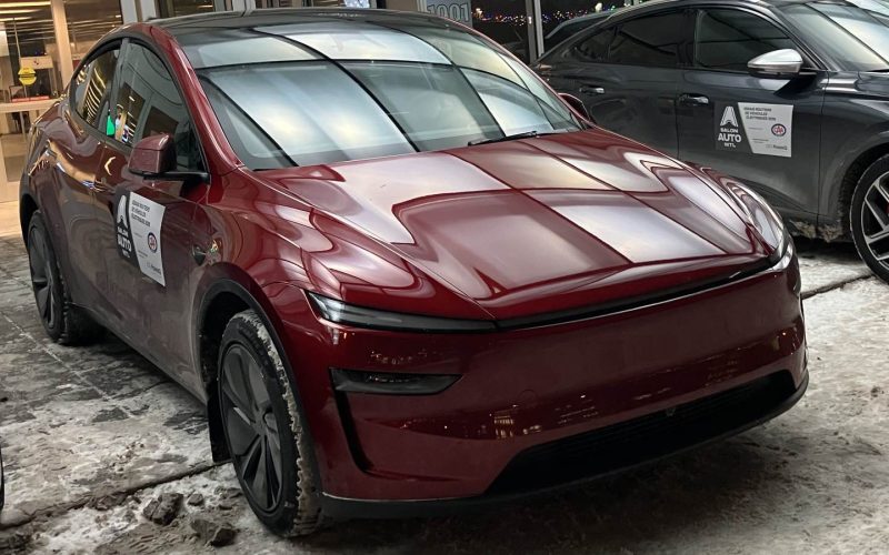 Red 2026 Tesla Model Y parked on a snowy sidewalk outside the Montreal International Auto Show