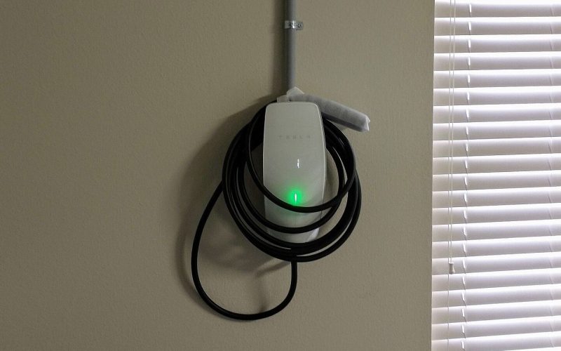 Tesla Wall Connector mounted on a garage wall with its charging cable coiled